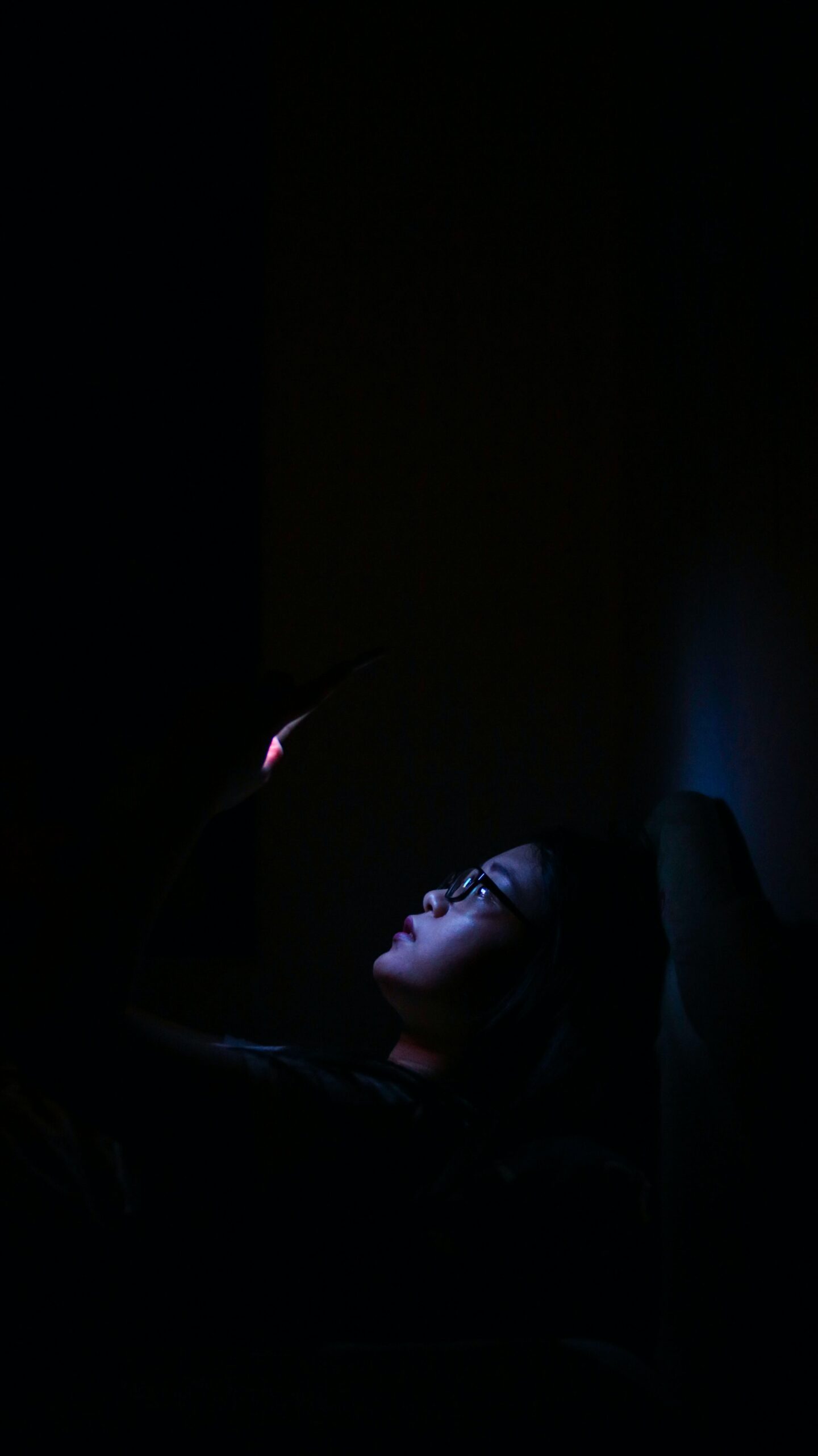 woman looking at phone at night in bed
