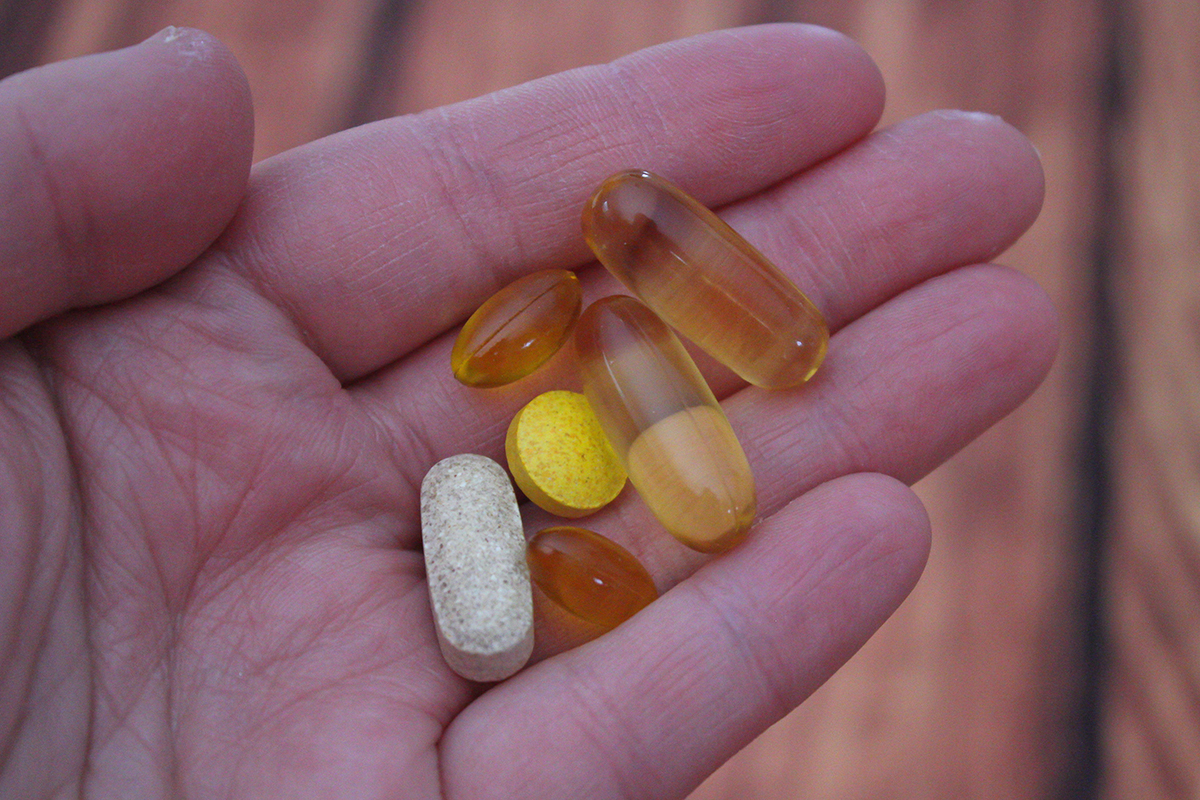 hand holding vitamin capsules and tablets